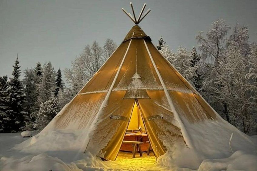A snow-covered teepee with a warm interior light, surrounded by a snowy landscape and trees. 5