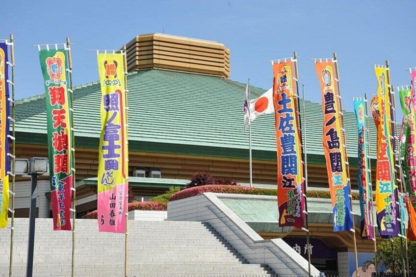 Un edificio con techo verde y múltiples banderines de colores con texto japonés. 3