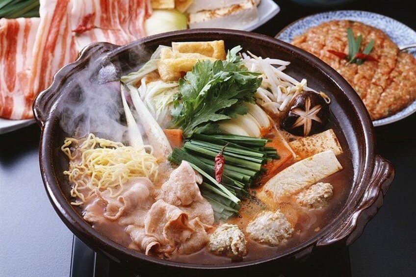 Una olla caliente con diversos ingredientes como fideos, tofu y verduras. 4