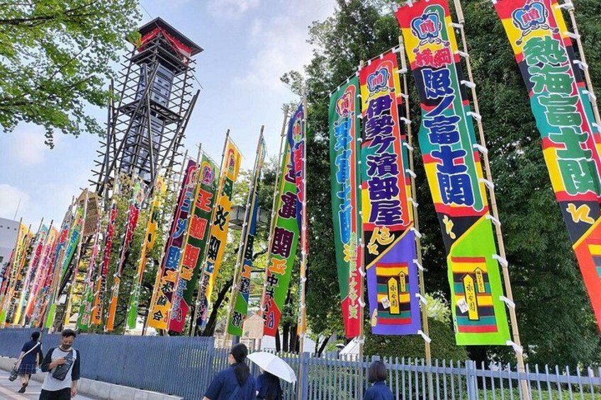 Una fila de banderas coloridas con texto, una torre de metal y una valla blanca. 2