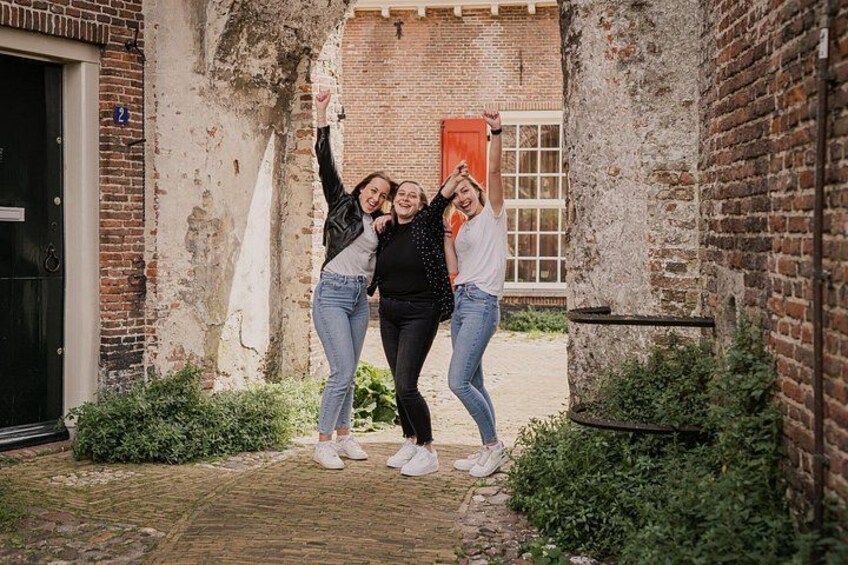 Three people standing in an alleyway with brick walls and a door. 2