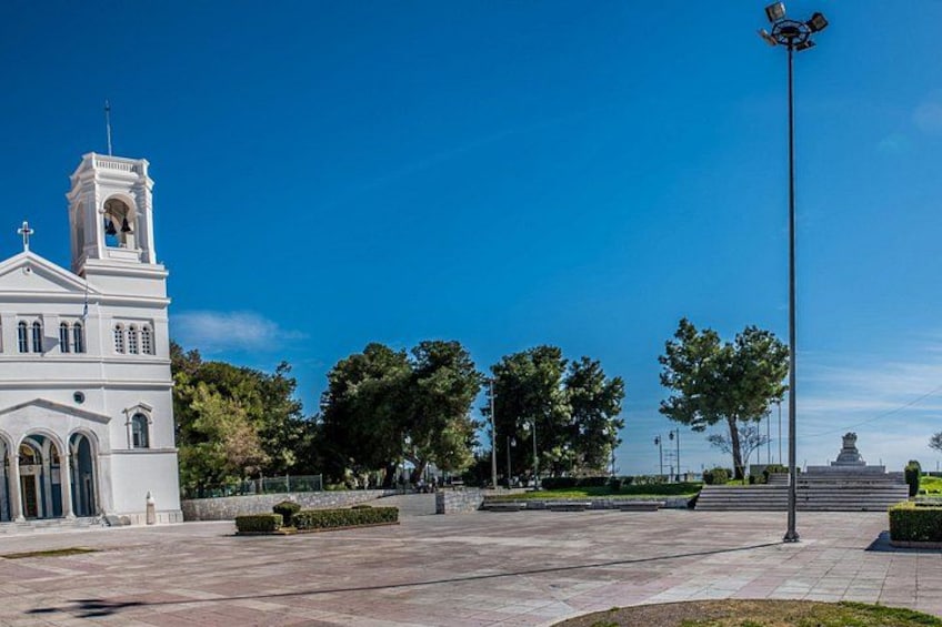 Una iglesia blanca con un campanario, rodeada de árboles y un cielo azul despejado. 3