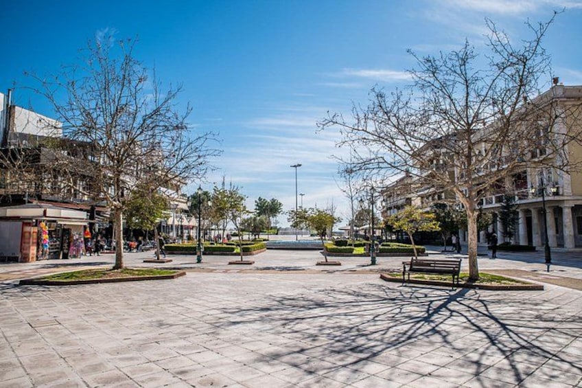 Una plaza empedrada con bancos, árboles y edificios. 2