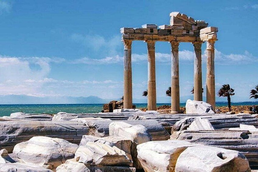 Ancient ruins with columns and large stone blocks, set against a clear blue sky and sea. 5