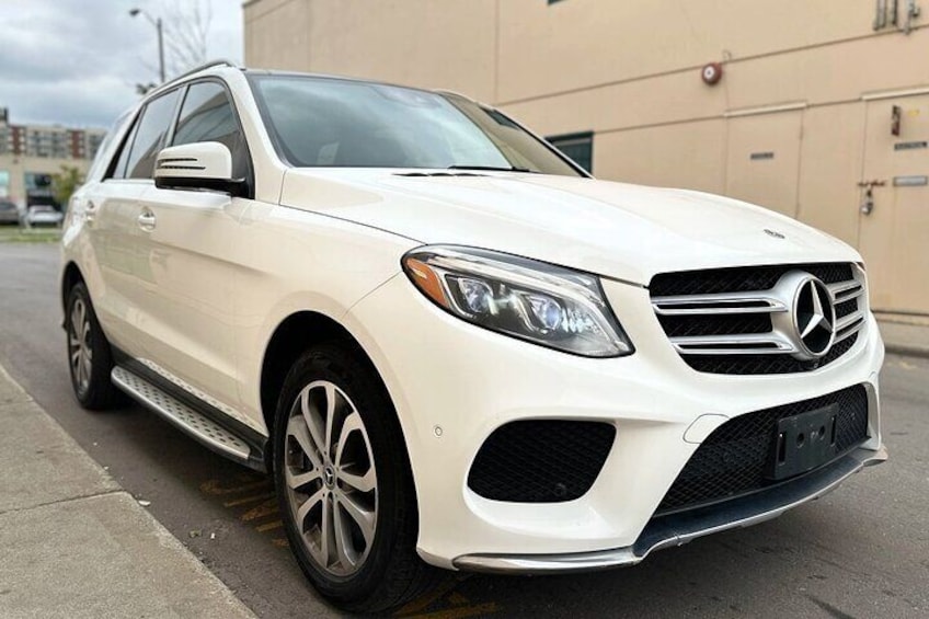 A white Mercedes-Benz SUV parked on a street. 5