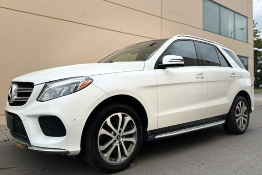 A white SUV parked in front of a building with large windows. 1