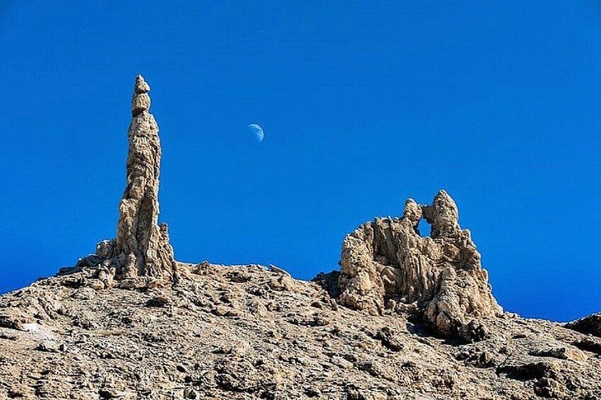 A rocky landscape with a prominent rock formation and a crescent moon in the sky. 2