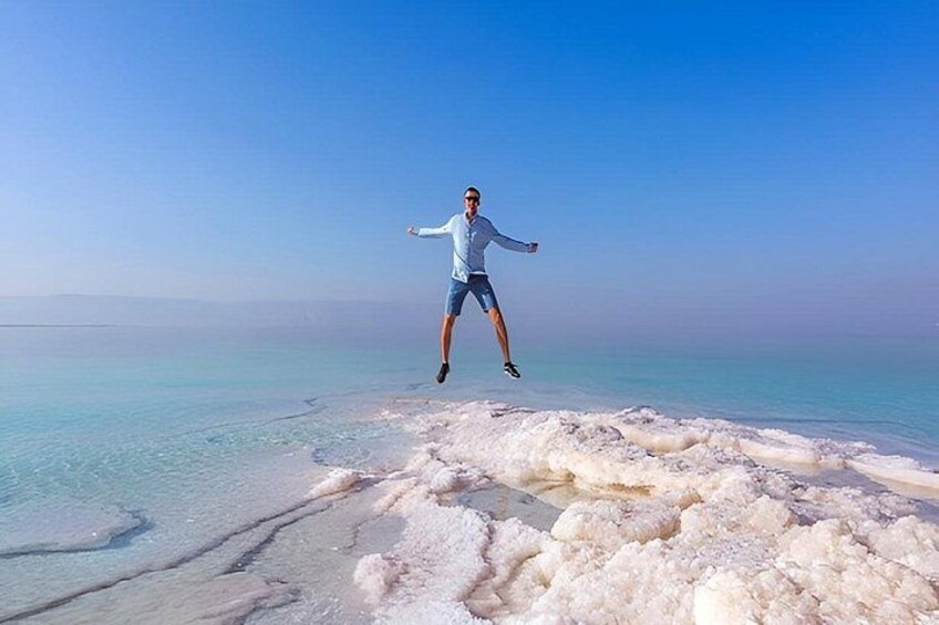 A person jumping on a salt flat with a clear sky. 3