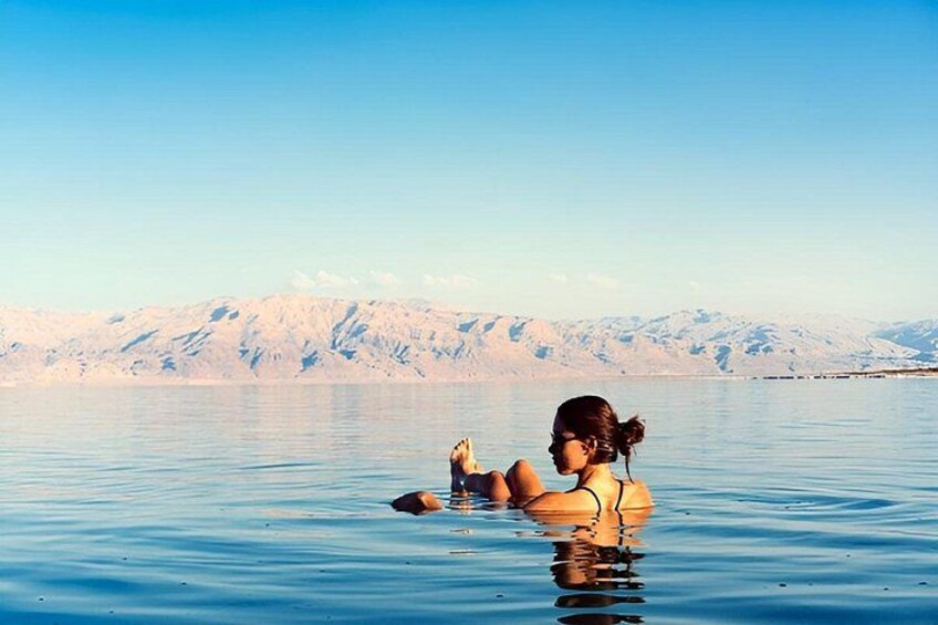A person floating in a body of water with mountains in the background. 5