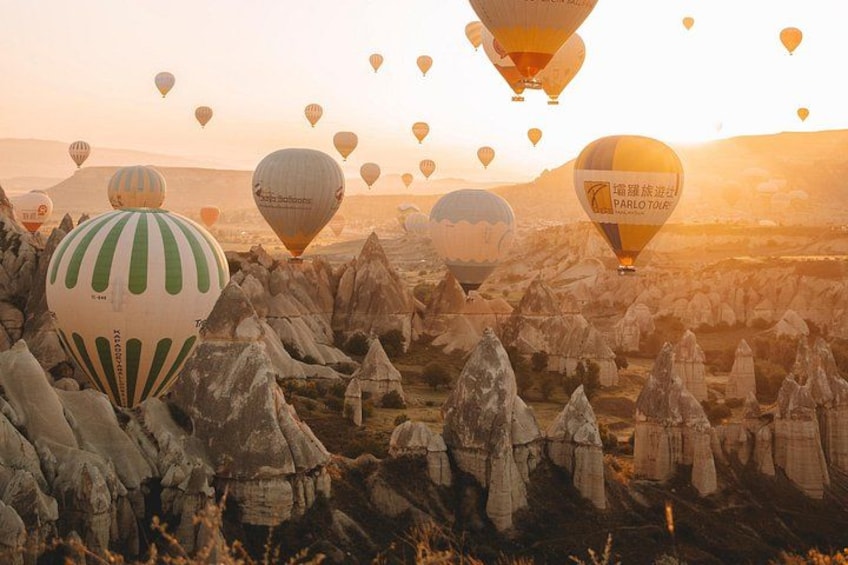 Ett landskap med många varmluftsballonger och klippformationer. 1