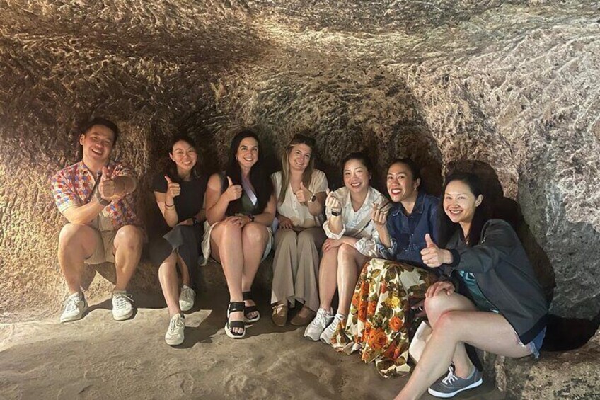 Un groupe de personnes est assis dans une grotte, avec une paroi rocheuse en arrière-plan. 3