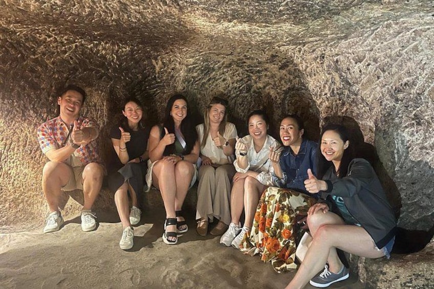 En grupp människor sitter i en grotta med en bergvägg bakom sig. 3