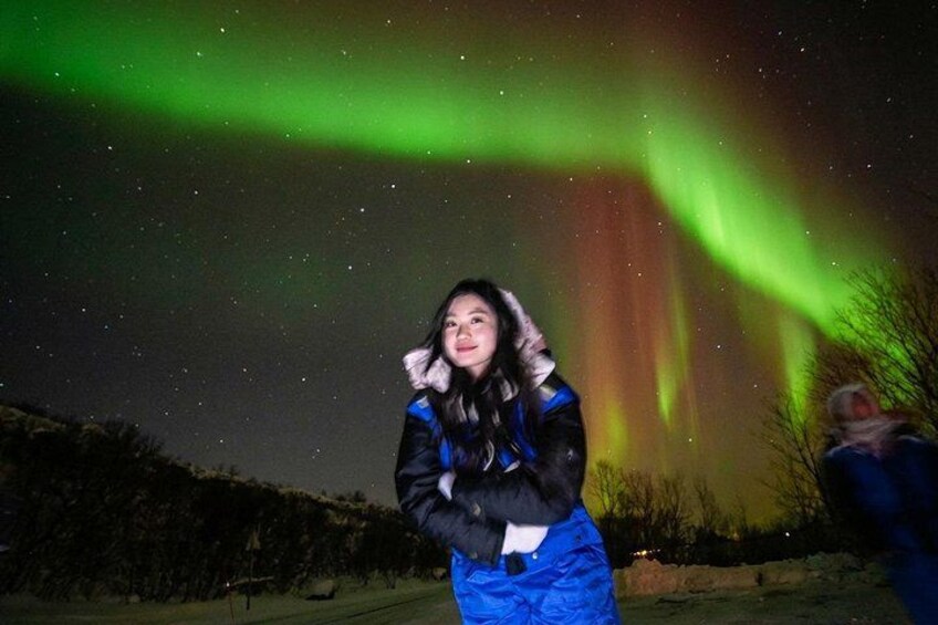 A person standing outdoors at night with the Northern Lights in the background. 5