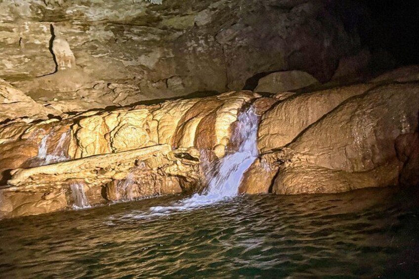A cave with a waterfall and illuminated rock formations. 5