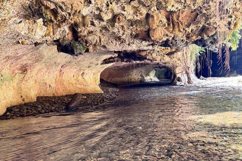 A cave entrance with a large rock formation overhanging the water. 2