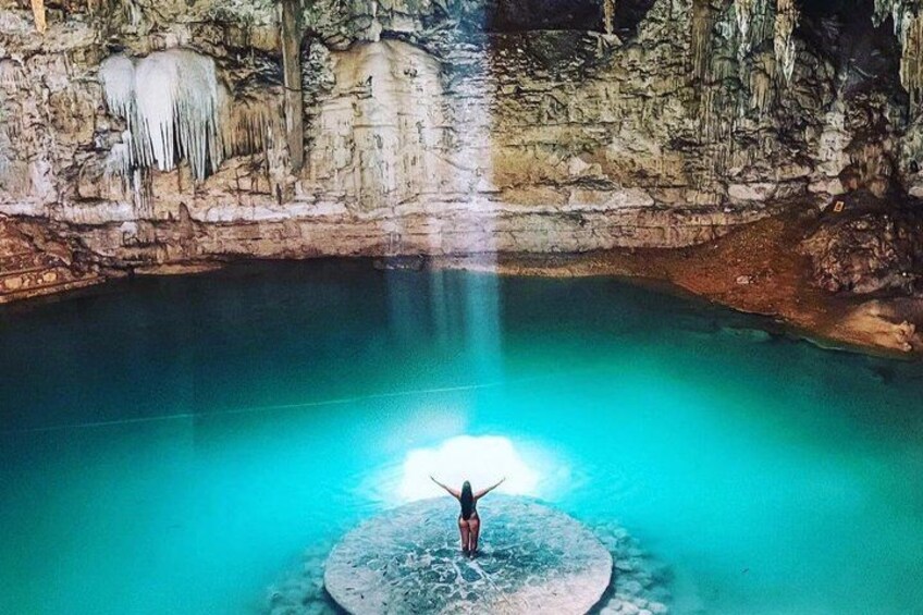 Une personne se tient sur une plateforme dans une grotte, au bord d’une étendue d’eau, avec des stalactites au plafond. 5