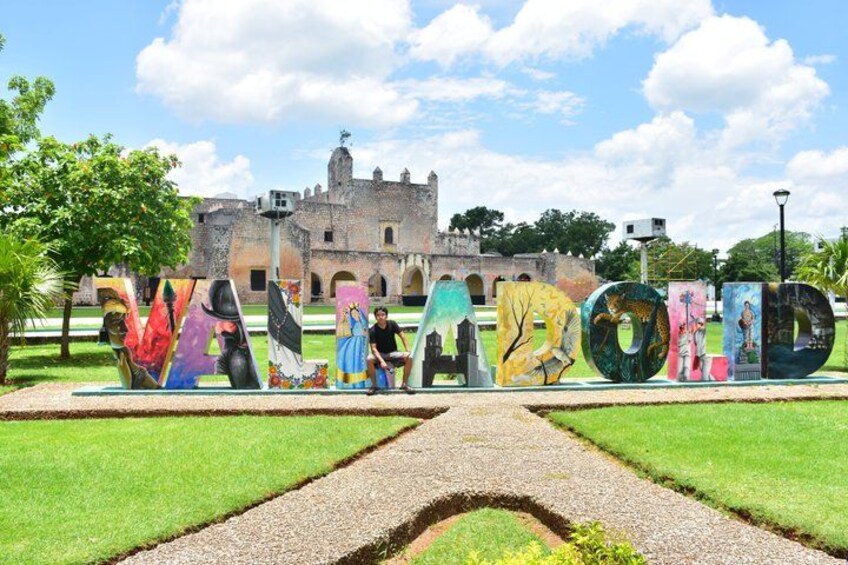 Un jardin agrémenté de sculptures abstraites aux couleurs vives, avec un bâtiment historique en arrière-plan. 2