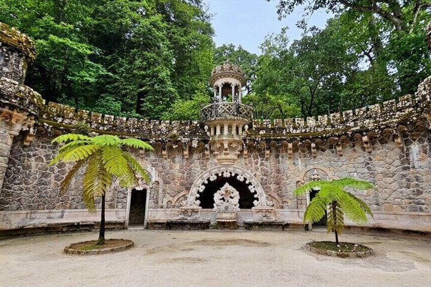 A stone structure with a central tower, surrounded by trees and a stone wall. 2