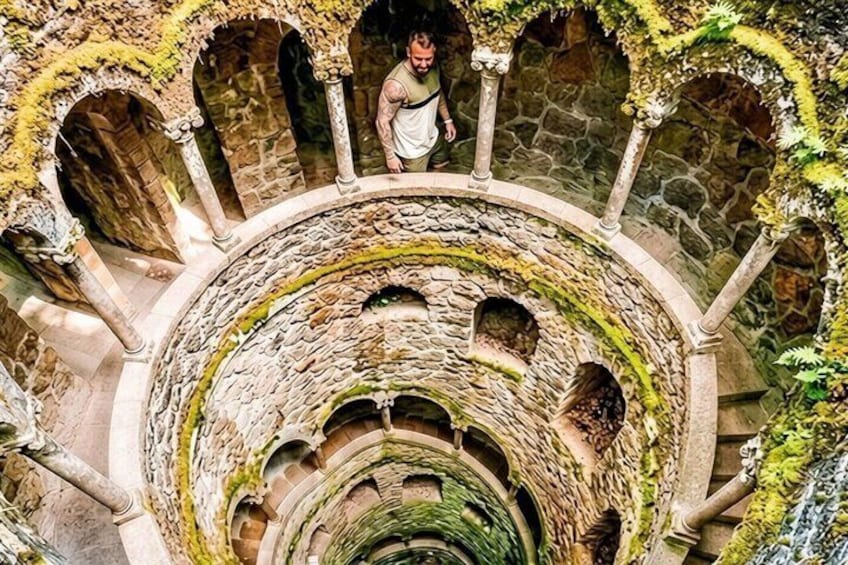 A spiral stone staircase with arches and moss-covered walls. 1