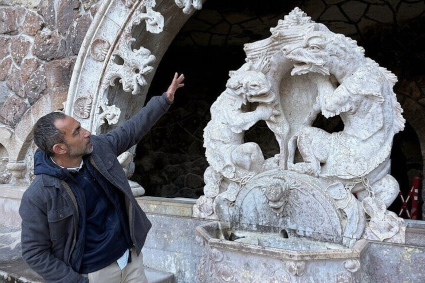 A person pointing at a stone sculpture of a mythical creature. 5