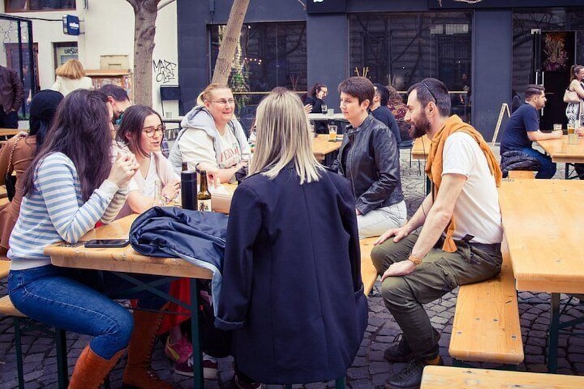 People sitting at outdoor tables, engaged in conversation. 3