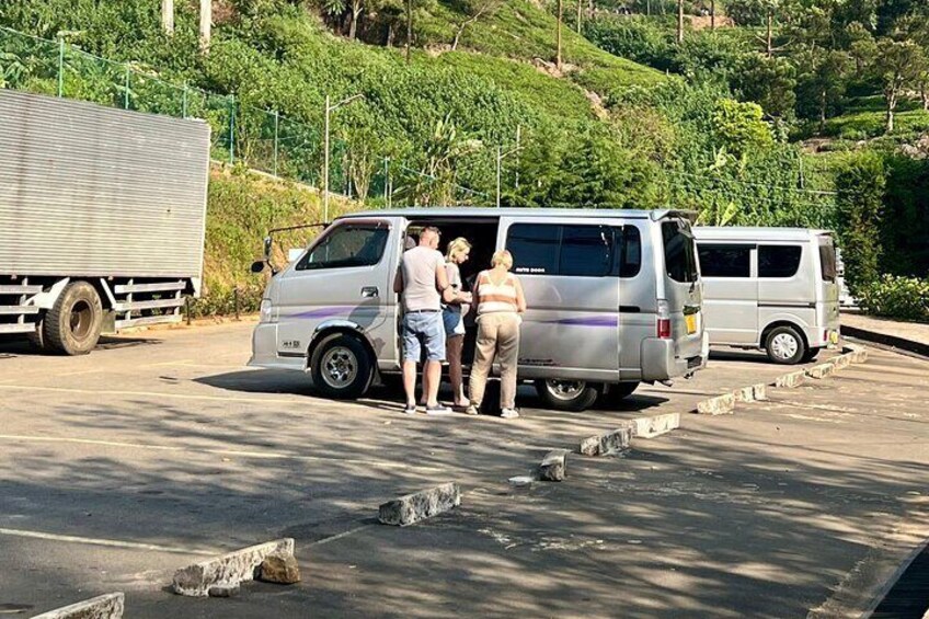 Una camioneta plateada estacionada en una carretera, con tres personas de pie junto a ella. 2