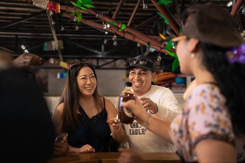 A group of people sitting at a table in a restaurant with a rustic ceiling and hanging decorations. 4