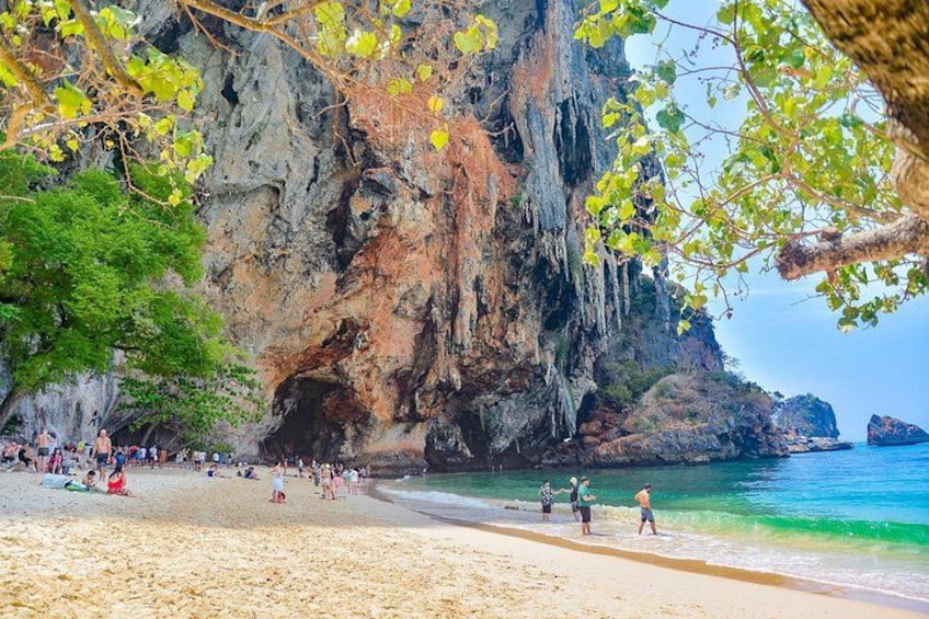 A beach with people, a rocky cliff, and clear blue water. 5