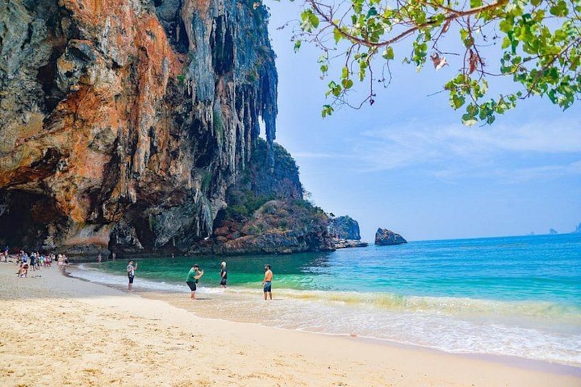A beach with clear turquoise water, sandy shore, and rocky cliffs. 4