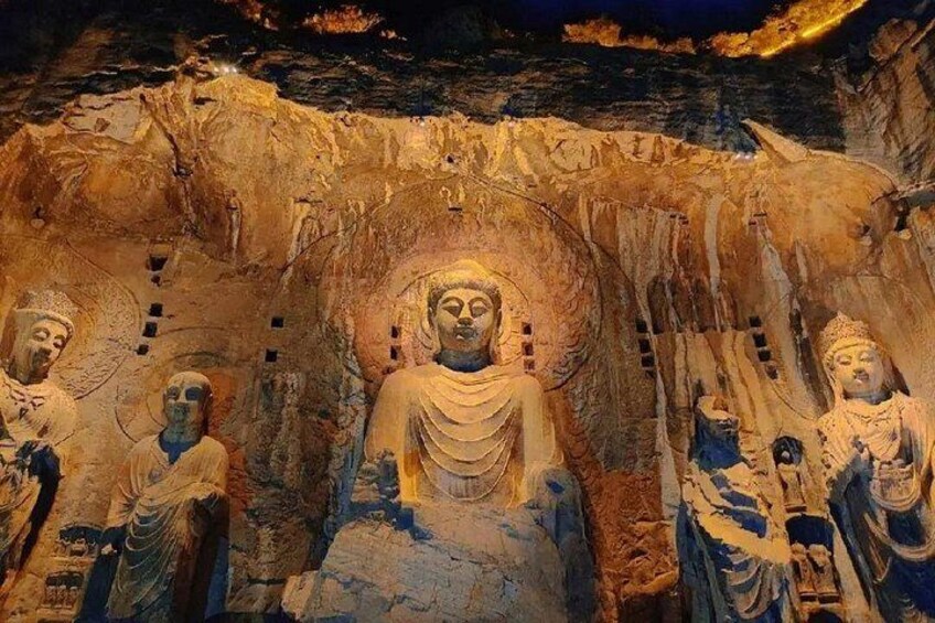 A large Buddha statue surrounded by smaller statues in a cave. 1