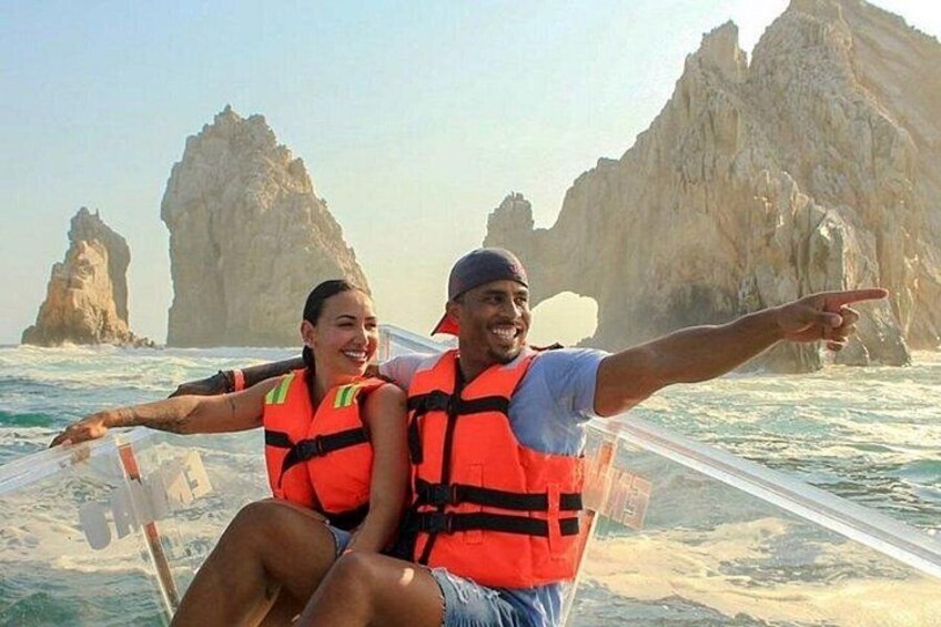 Dos personas en un bote con chalecos salvavidas, señalando hacia acantilados rocosos al fondo. 4