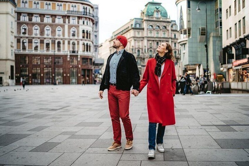 A couple holding hands in a public square with historic buildings in the background. 2