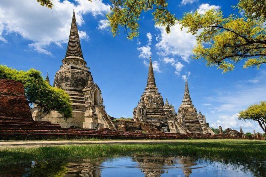 Ancient temple ruins with tiered structures and a calm pond in the foreground. 4