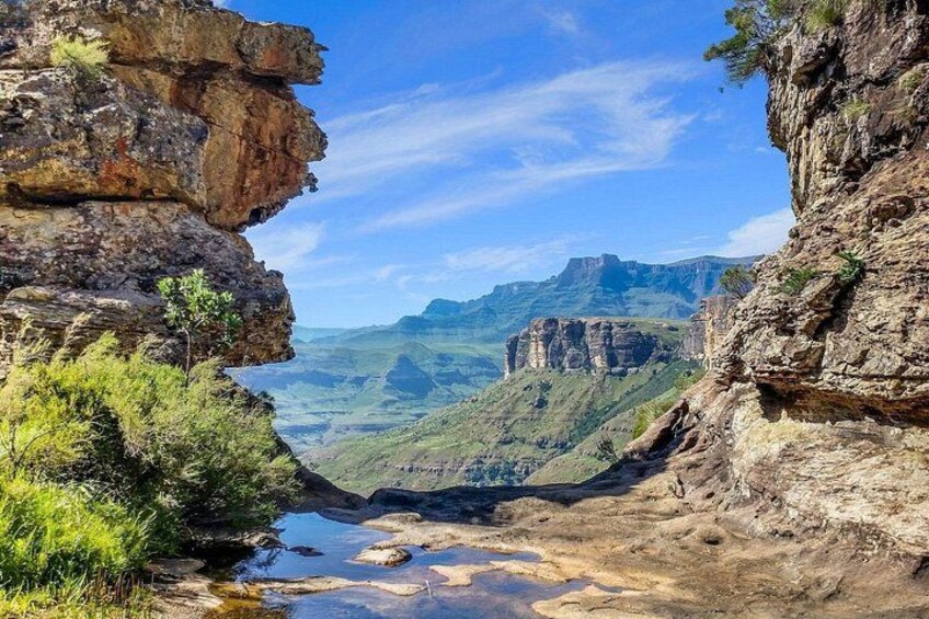 Un canyon con formazioni rocciose ripide, un fiume e montagne in lontananza. 5