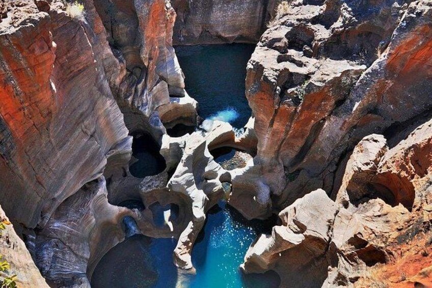 A canyon with a deep blue pool surrounded by rocky cliffs. 2