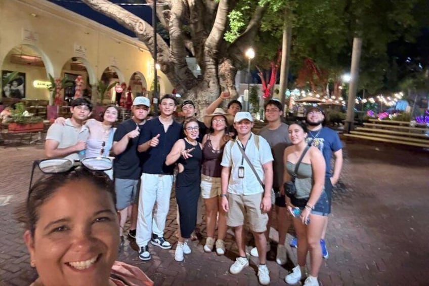 Un grupo de personas posando al aire libre, con un árbol y un edificio en el fondo. 3
