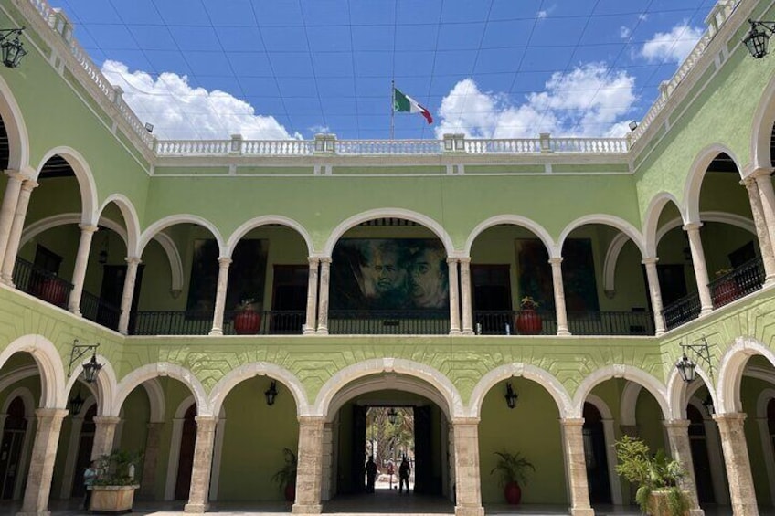 Un patio con paredes verdes, arcos blancos y una bandera. 1