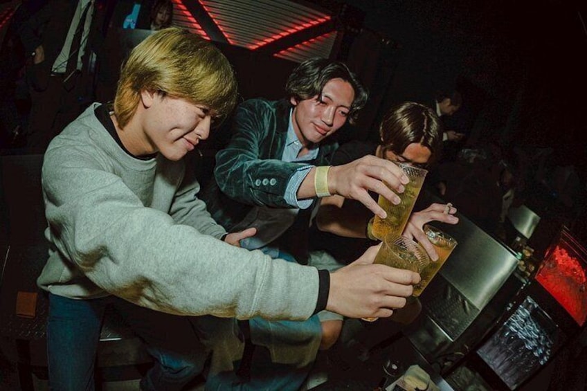 Personas en un bar con poca luz, sosteniendo bebidas. 5