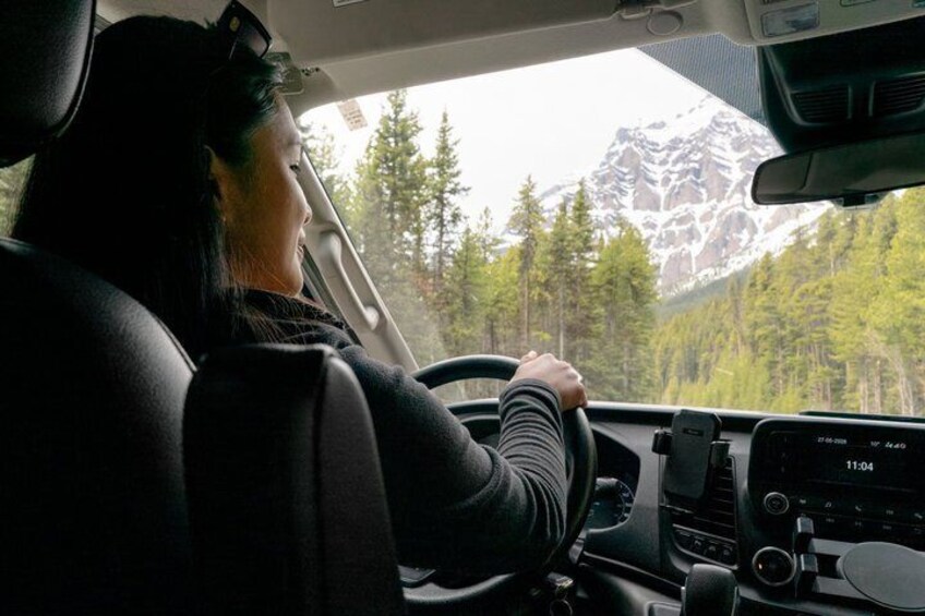 A person driving a car with a mountainous landscape visible through the windshield. 2
