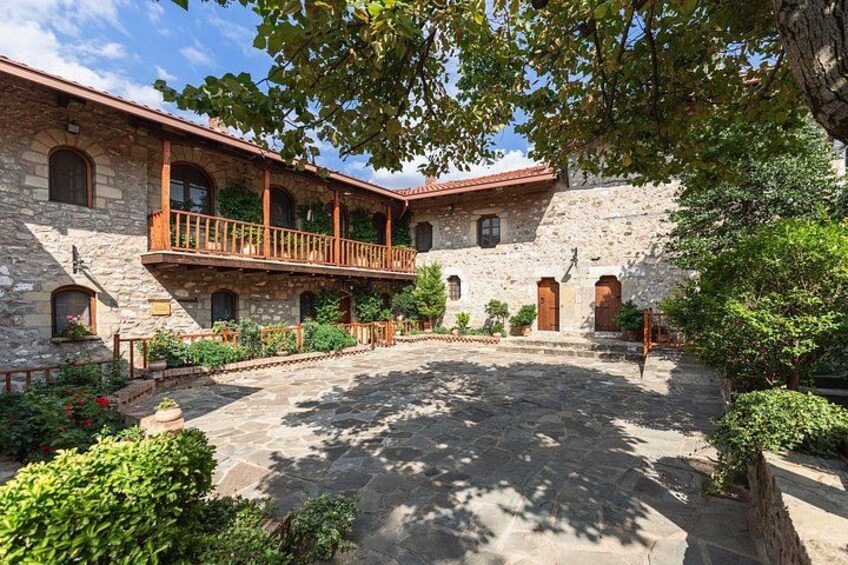 A stone building with a courtyard, wooden balcony, and potted plants. 3