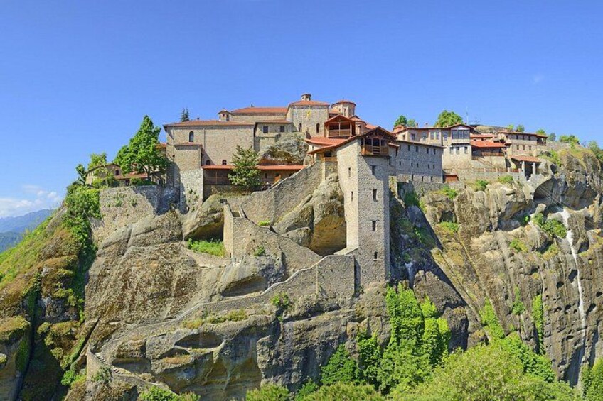 A historic stone building perched on a rocky cliff with lush greenery. 4
