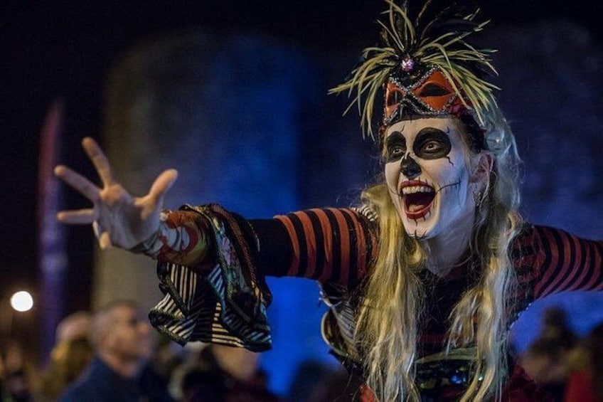 A person in a colorful costume with a feathered headpiece, extending their hand outward. 3