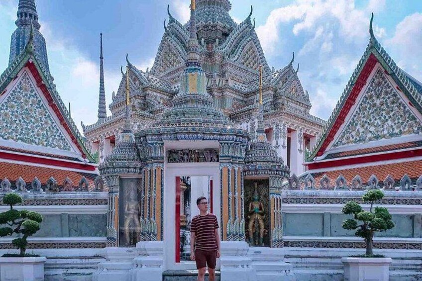 A person standing in front of a temple with intricate architecture and a red door. 3