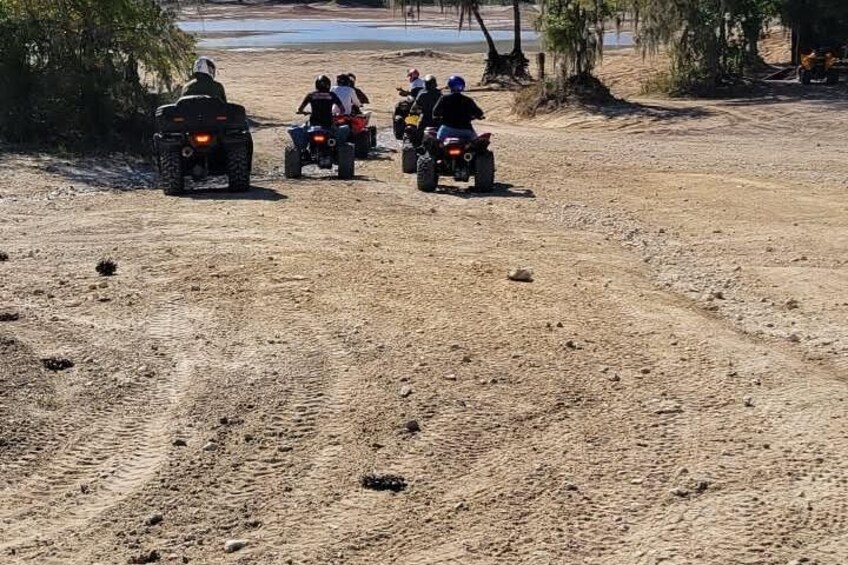 A group of people riding ATVs on a dirt path. 1
