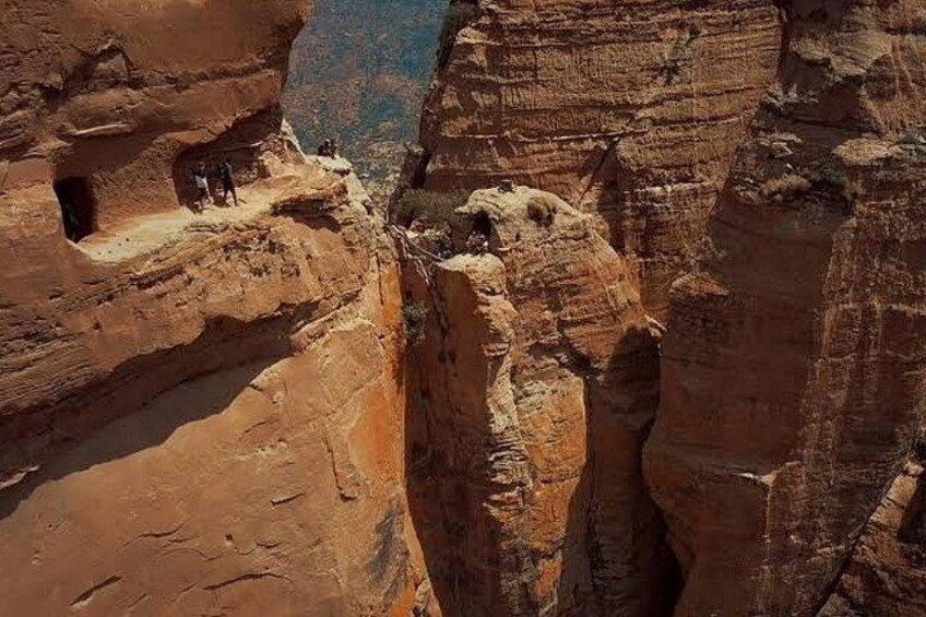 A canyon with rock formations and a small cave entrance. 5