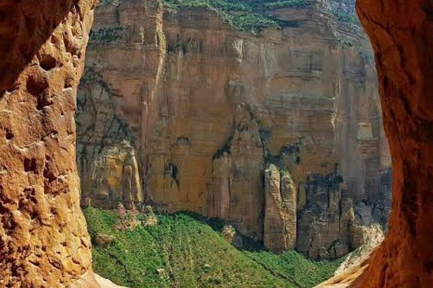 A canyon with rock formations and greenery. 2