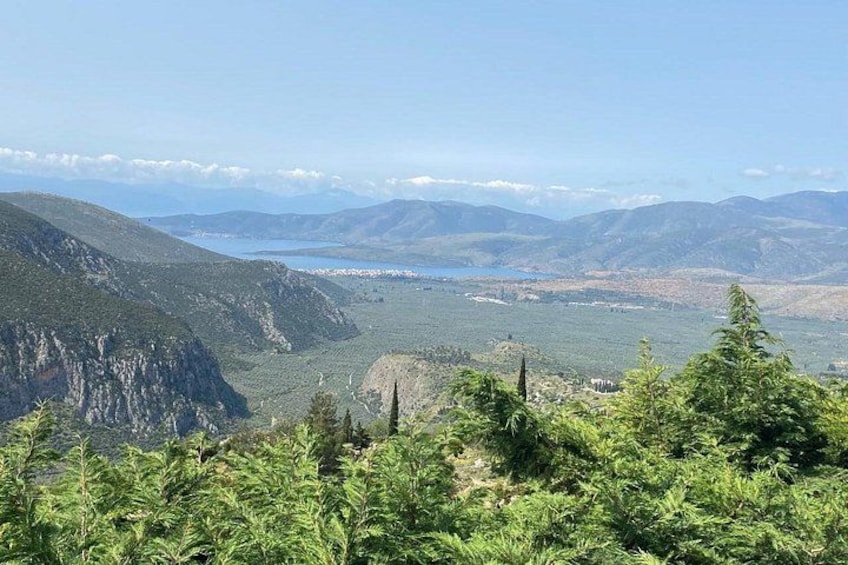 Eine gebirgige Landschaft mit einem Tal, einem See und einer in der Ferne liegenden Stadt. 3