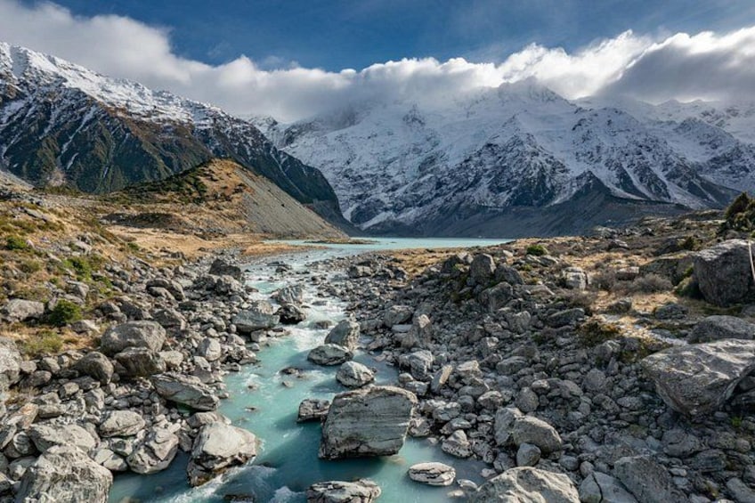 A river flowing through a rocky landscape with snow-capped mountains in the background. 5
