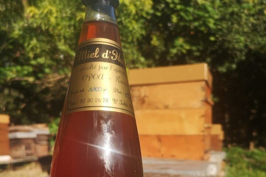 A bottle with a label, set against a backdrop of trees and a wooden structure. 2