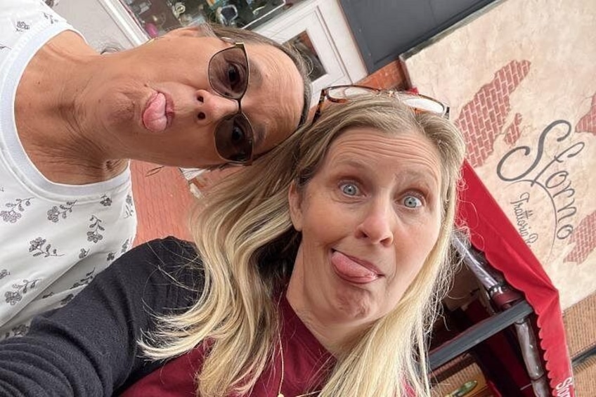 Two people taking a selfie with a storefront in the background. 2